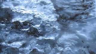 Spring melt under frozen waterfall, bubbles racing