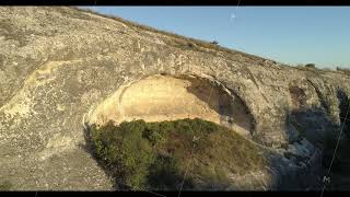 Huge round hole on a mountain slope. Shot. Geological formation