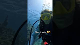 female scuba diver having fun underwater with her regulator and also picking up trash underwater