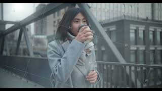 Asian girl walks along a bridge crossing against the backdrop of a city landscape. Happy girl