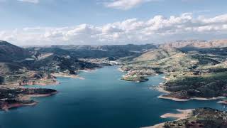 A Dam Between A Series Of Mountains And Hills With Beautiful Bird Chirping And Wind Blowing