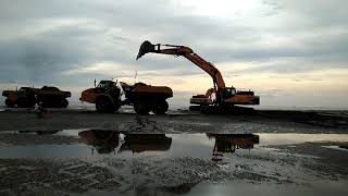 From the distant sea, I saw a large truck with two excavators