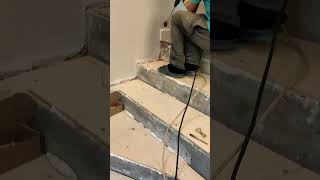 Laying the motion sensor cable on the stairs using a hammer drill