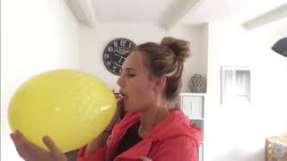 Girl blows up an enormous yellow balloon until it pops