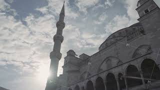 Bottom view of an ancient beautiful mosque on the background of blue cloudy sky and shining sun